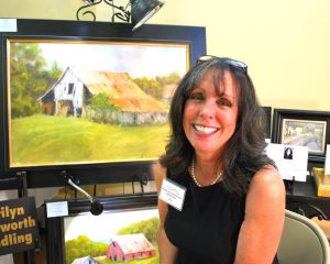 Marilyn Wendling smiles in front of one of her impressionistic paintings. 